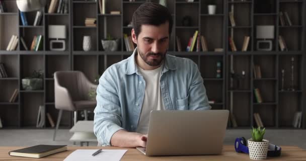 Komoly elfoglalt ember ül a munkahelyen íróasztal sms-ező laptopon — Stock videók