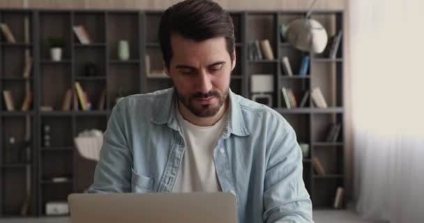 Sonriente hombre sentarse en el escritorio usando el ordenador portátil disfrutar de la comunicación remota — Vídeo de stock