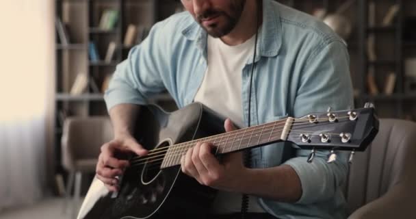 Close up view man playing acoustic guitar seated in office — Stock Video