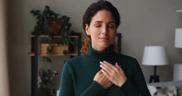 Piękna szczera kobieta stoi wewnątrz umieścić złożone dłonie na sercu — Wideo stockowe