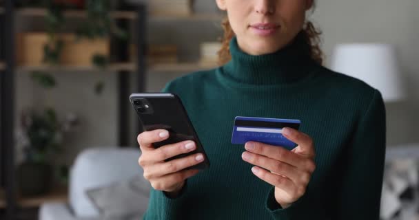 Woman holding smartphone and credit card makes secure payment closeup — Stock Video