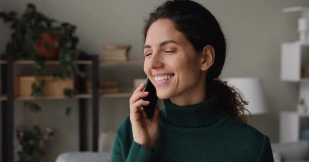 Mujer bastante joven en cuello alto teniendo una conversación agradable en el teléfono inteligente — Vídeos de Stock