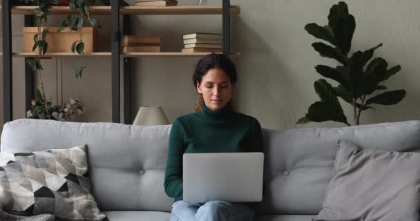 Mulher sentada no sofá na sala de estar mensagens de texto no laptop — Vídeo de Stock