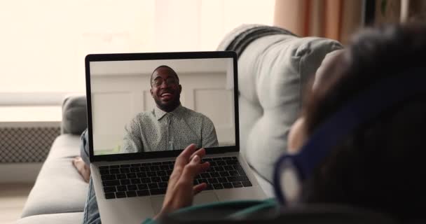 Kvinna bär hörlurar prata med afrikanska vän genom videosamtal — Stockvideo