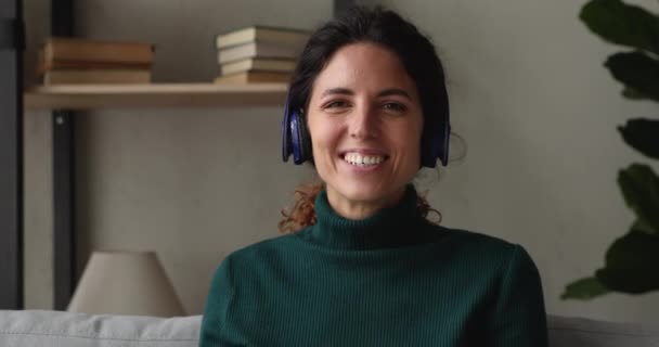 Femme dans les écouteurs regardant la caméra parler par appel vidéo — Video