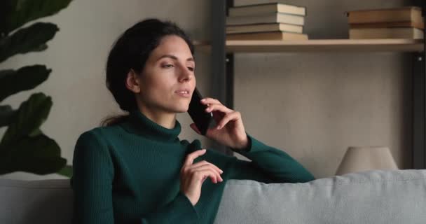 Mujer sentada en el sofá en casa hablando por teléfono — Vídeo de stock