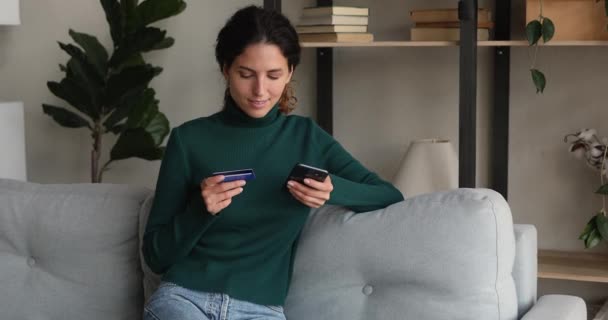 Mulher segurando smartphone e cartão de crédito faz pagamento seguro — Vídeo de Stock