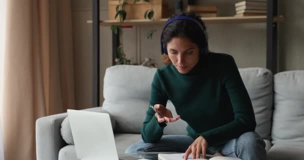 Frau trägt Kopfhörer im Gespräch mit Online-Tutor per Laptop-App — Stockvideo