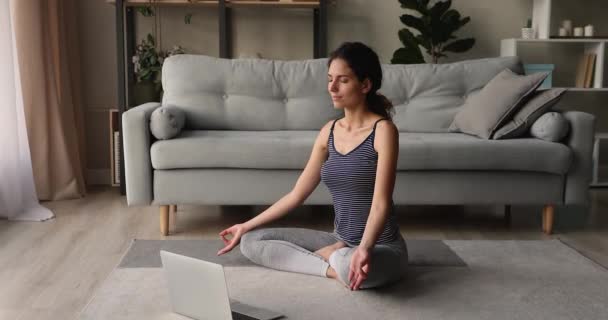 Sereno mulher sentar de pernas cruzadas meditando ouvir música no laptop — Vídeo de Stock
