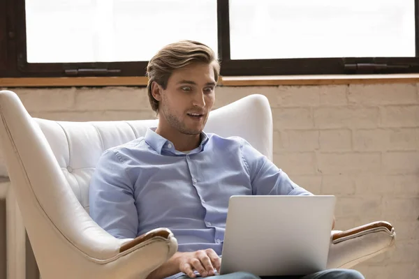 Verbijsterde man geschokt door nieuws op laptop — Stockfoto