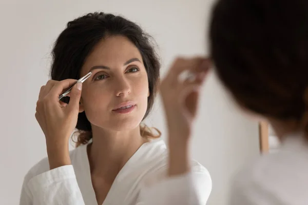 Jovem mulher prepare-se beliscar sobrancelhas no banheiro — Fotografia de Stock