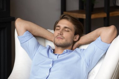 Genç adam sandalyede rahatla ve evinde uyu.