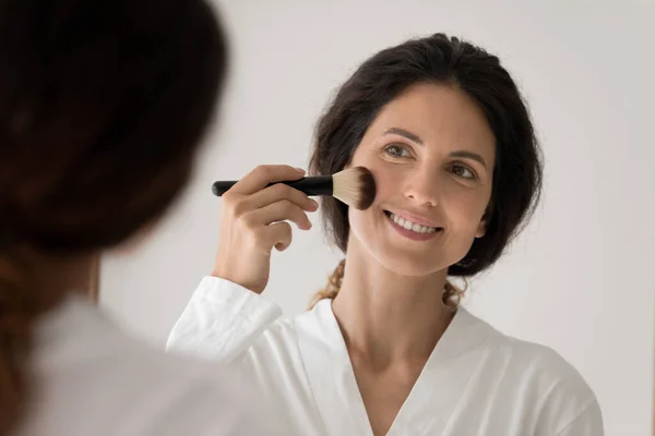 Szczęśliwa młoda kobieta patrzeć w lustrze robi makijaż — Zdjęcie stockowe