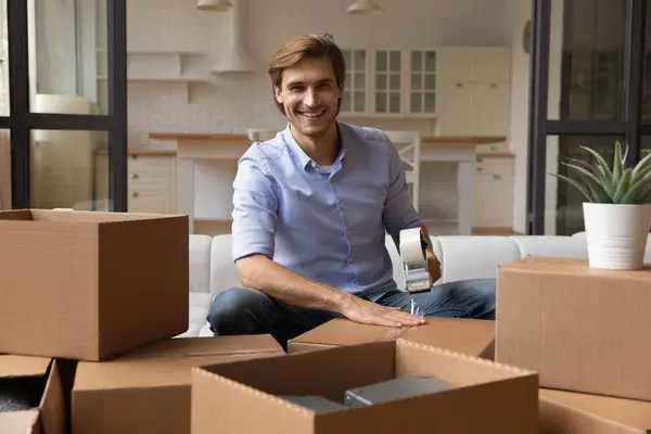 Portrait of smiling man pack boxes relocating to new home