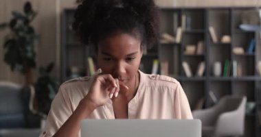 Dizüstü bilgisayara bakan odaklanmış Afrikalı kadın yeni bir uygulama öğreniyor