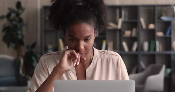 Focalizzato donna africana guardando il computer portatile imparare una nuova app — Video Stock