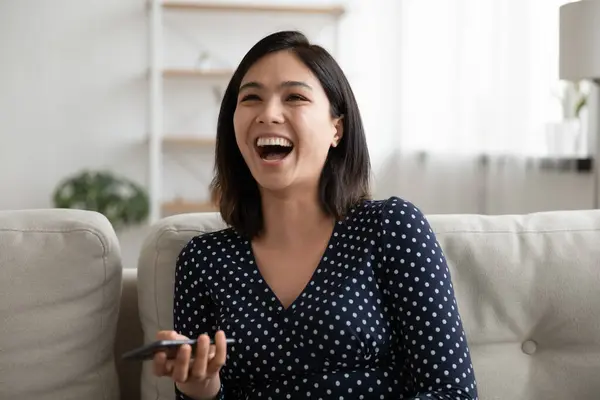 Emotionele gelukkig duizendjarige aziatische vrouw lachen om grappige mobiele video. — Stockfoto