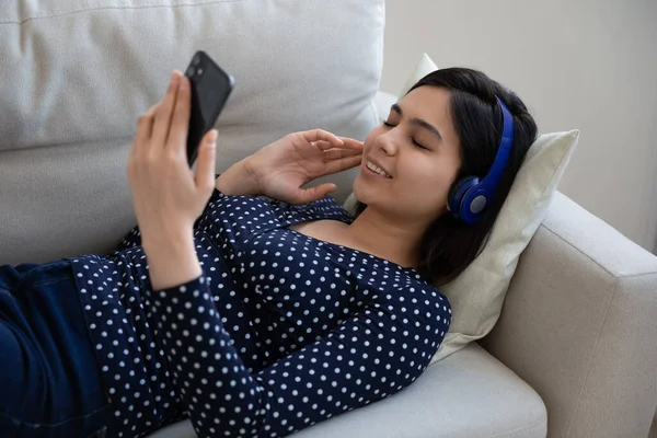 Ontspannen glimlach millennial aziatische vrouw luisteren muziek in hoofdtelefoon. — Stockfoto