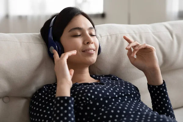 Serene jonge mooie Koreaanse vrouw luisteren muziek in hoofdtelefoon. — Stockfoto