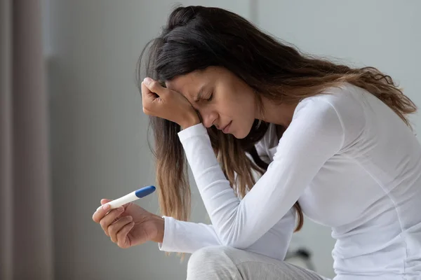 Закрыть несчастную женщину, проводящую тест на беременность, трогающую лоб — стоковое фото