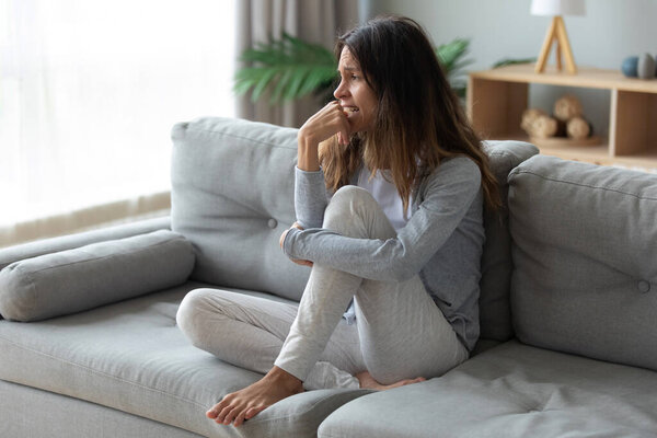 Depressed unhappy woman crying, sitting on couch alone
