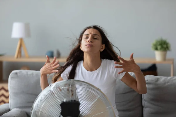 Αστεία υπερθερμαίνεται γυναίκα απολαμβάνοντας καθαρό αέρα, ψύξη από ηλεκτρικό ανεμιστήρα — Φωτογραφία Αρχείου