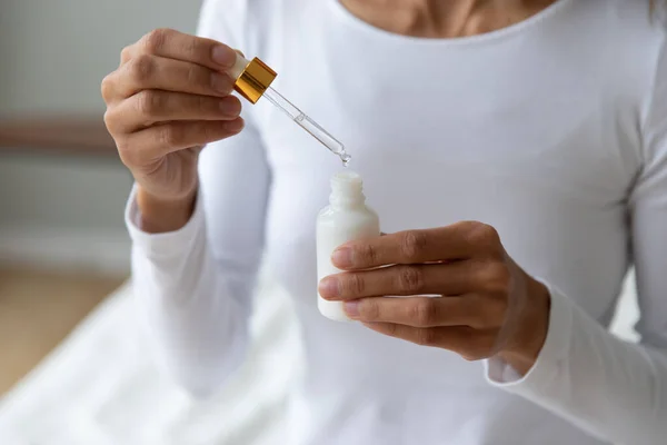 Nahaufnahme Frau hält Flasche mit Kosmetikserum, Hautpflegekonzept — Stockfoto