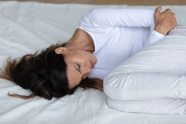 Menutup bahagia wanita yang menderita sakit perut, berbaring di tempat tidur — Stok Foto