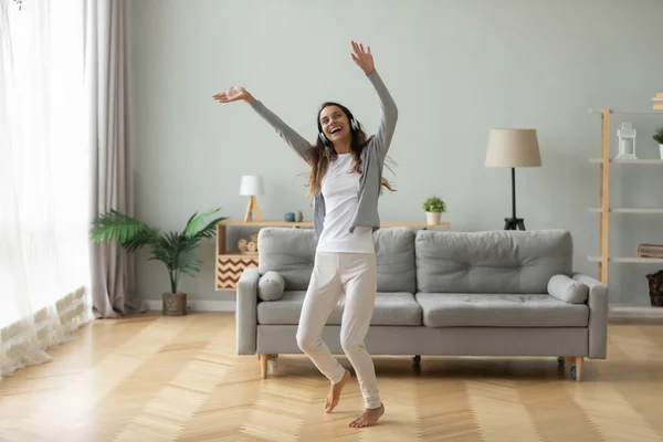 Een vrolijke vrouw met een hoofdtelefoon dansend in de moderne woonkamer. — Stockfoto