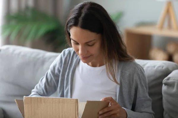 Close up mulher curiosa espreitando na caixa de papelão, recebeu parcela — Fotografia de Stock