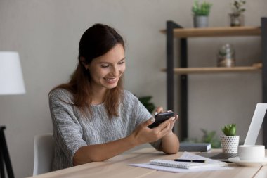 Gülümseyen kadın internetteki cep telefonu ekranına bak.