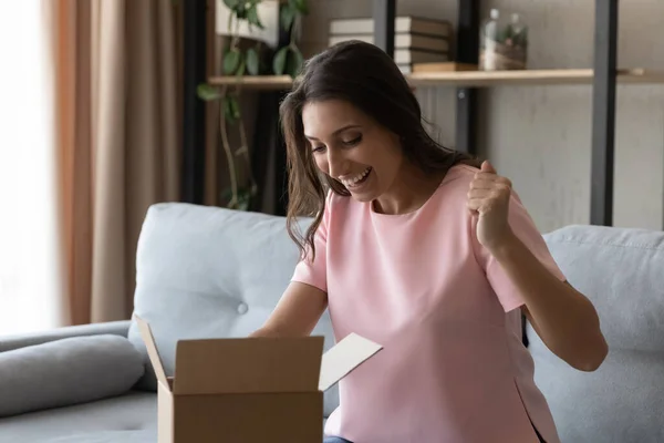 Vzrušená mladá žena rozbalit balíček s internetovou objednávkou — Stock fotografie
