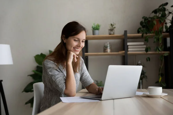 Donna sorridente lavoro lontano sul computer portatile a casa — Foto Stock