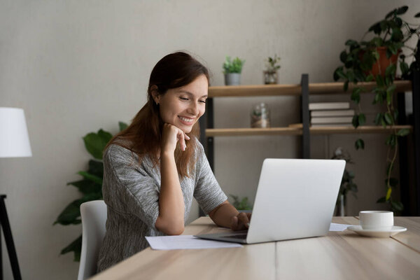 Smiling woman work distant on laptop at home