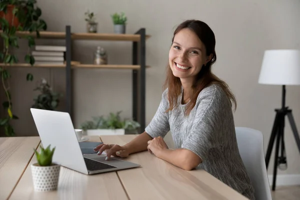 Портрет улыбающейся женщины, использующей ноутбук дома — стоковое фото