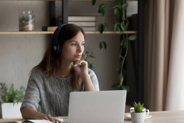 Pensive woman in headphones work on laptop thinking — Stock Photo, Image