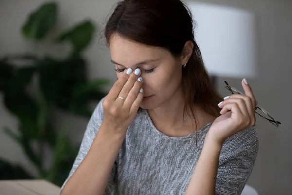 Unavená mladá žena masírovat oči trpí bolestí hlavy — Stock fotografie