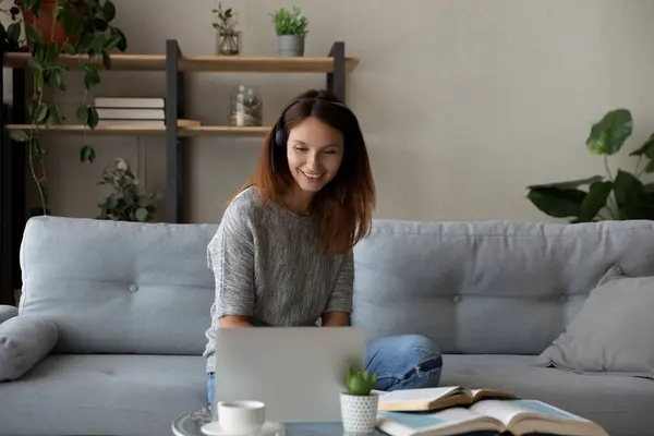 Leende kvinna i hörlurar studerar online hemma — Stockfoto