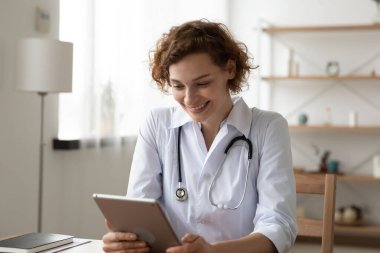 Mutlu 35 'ler kadın doktoru dijital tablette yazılım uygulaması kullanıyor.