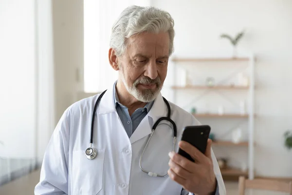 Starší muž středního věku lékař pomocí aplikací smartphone. — Stock fotografie