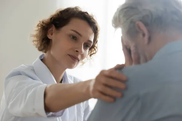 Mitfühlender junger Allgemeinmediziner unterstützt verzweifelten Mann. — Stockfoto