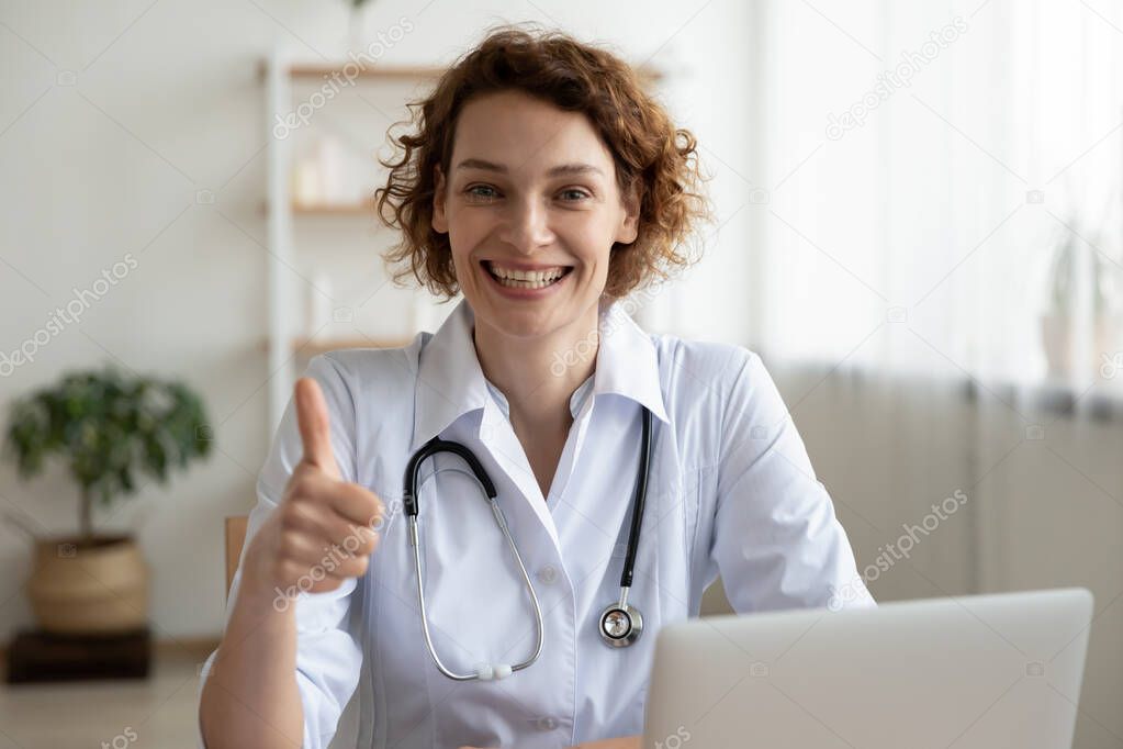 Portrait of happy young female doctor showing thumbs up gesture.