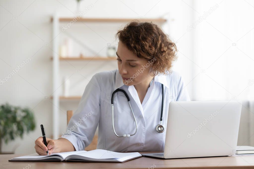 Concentered young female general practitioner involved in paperwork.