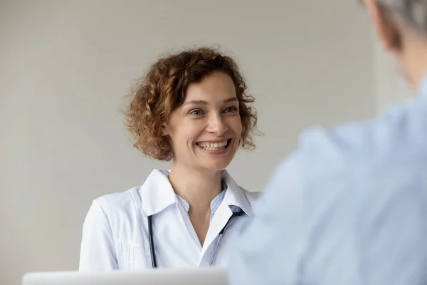 Счастливая молодая красивая женщина-терапевт слушает пациента. — стоковое фото