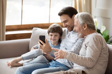 Mutlu üç nesil erkek akıllı telefonu evde kullanır.