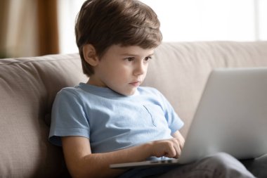 Akıllı çocuk evde dizüstü bilgisayar kullanıyor.
