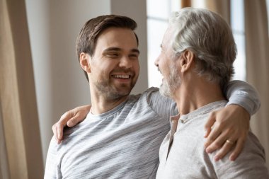 Aşırı mutlu yaşlı baba ve yetişkin oğul kucaklaşması.