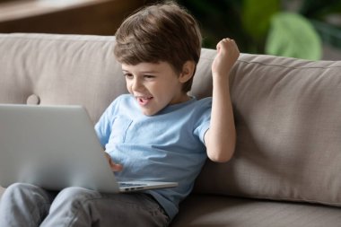 Mutlu küçük çocuk modern bilgisayarda oyun oynuyor.