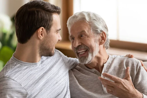 Happy mature dad and adult son talk at home — Stock Photo, Image