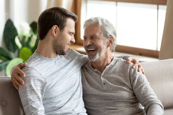 Smiling mature dad and grownup son relax together at home — Stock Photo, Image